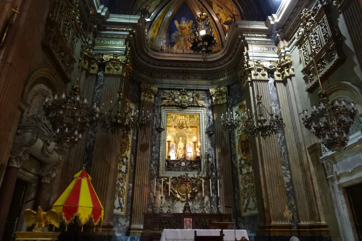 The high altar with marble columns, gilded ornament and hanging lamps.